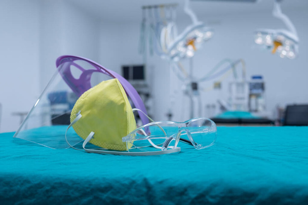 手術室で手術前に医師と看護師(手術用マスク、フェイスシールド、安全眼鏡など)の保護ヘッドウェアのグループ。covid-19発生における重要な対象の概念. - 写真・画像