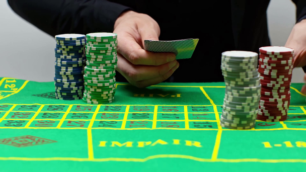 bijgesneden weergave van de mens trekken alle poker chips en het houden van speelkaarten - Video