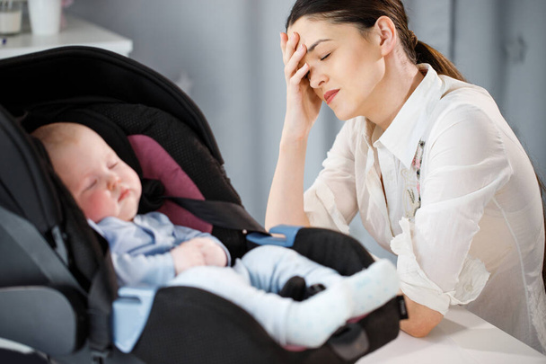Tired mother is sad near a sleeping child - Фото, изображение