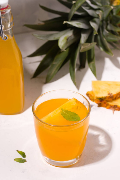 Ζυμωμένο kombucha ανανά καλοκαιρινό ποτό σε ένα λευκό πιάτο δίπλα στα συστατικά. Κάθετη φωτογραφία - Φωτογραφία, εικόνα