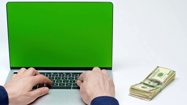 cropped view of man using laptop with green screen near money on white - Footage, Video