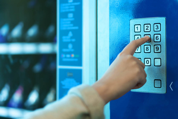 Dedo empurrando botão número na máquina de venda automática
 - Foto, Imagem