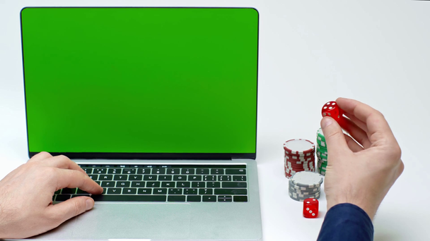 cropped view of player using laptop with green screen and holding dice on white - Footage, Video