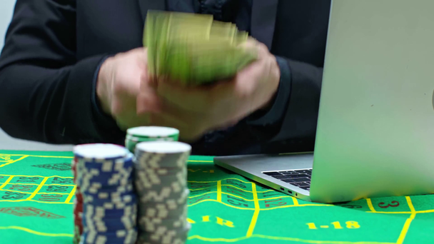 abgeschnittene Ansicht des Spielers, der Pokerchips zieht und Laptop benutzt - Filmmaterial, Video