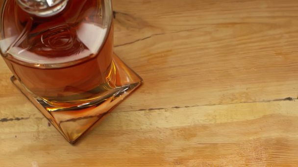 vue recadrée de l'homme tenant un verre de whisky près du décanteur sur une table en bois
 - Séquence, vidéo
