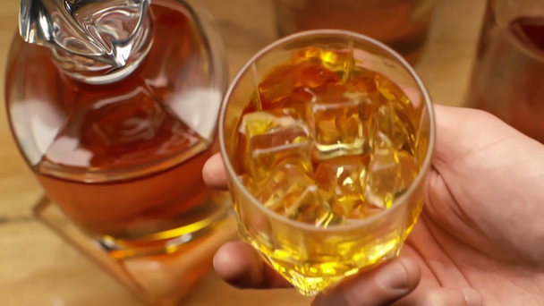 vue recadrée de l'homme tenant un verre de whisky avec des glaçons près du décanteur
  - Séquence, vidéo