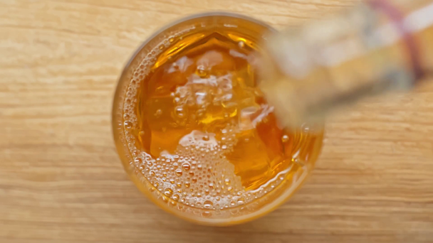 oříznutý pohled na člověka házejícího kostky ledu a nalévajícího whisky do skla  - Záběry, video