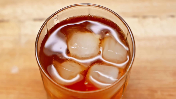 mieszanie whisky i kostek lodu w szklance z łyżeczką koktajlową - Materiał filmowy, wideo
