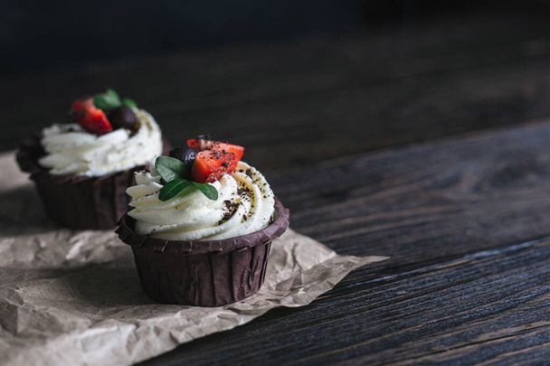 Sabroso cupcake, decorado con fresa fresca sobre un fondo de madera oscura. Lugar para el texto
. - Foto, imagen