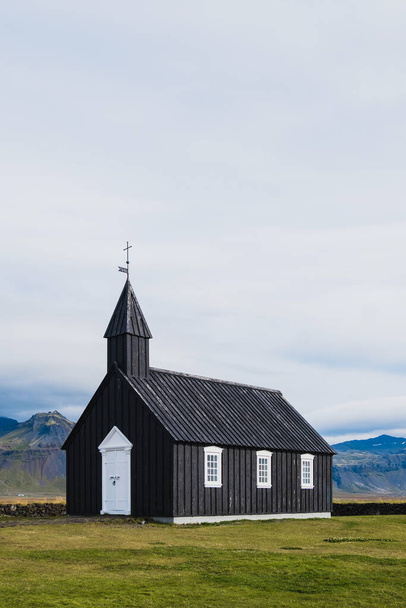 Black church in the meadow and field in Iceland. Icelandic scenic travel destination of religion. - Fotó, kép
