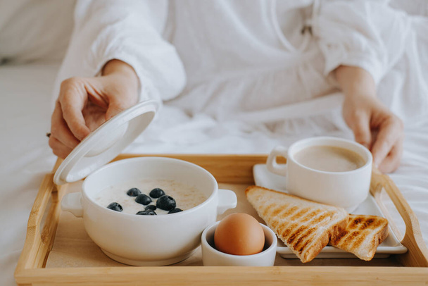 Breakfast in the hotel. Girl opens a pan with porridge - Zdjęcie, obraz