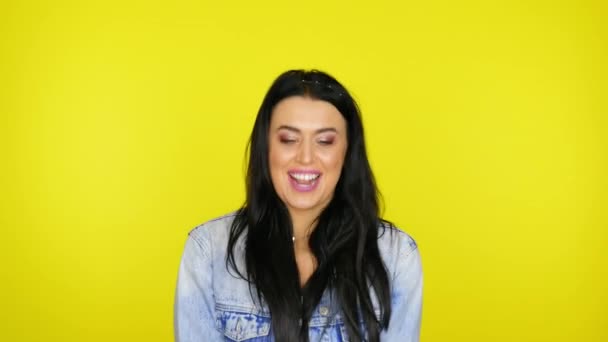 Cheerful woman throws up confetti on a yellow background with copy space - Video