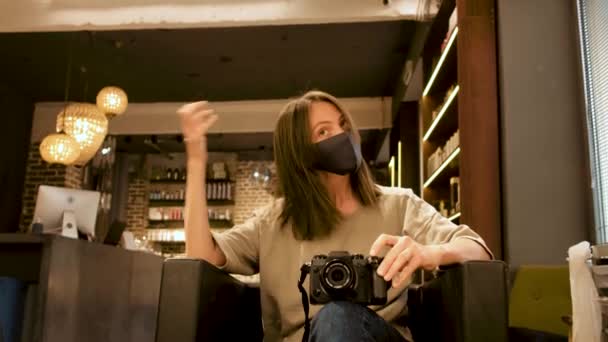 Mujer en máscara facial con cámara fotográfica digital delante del espejo en el salón
 - Imágenes, Vídeo