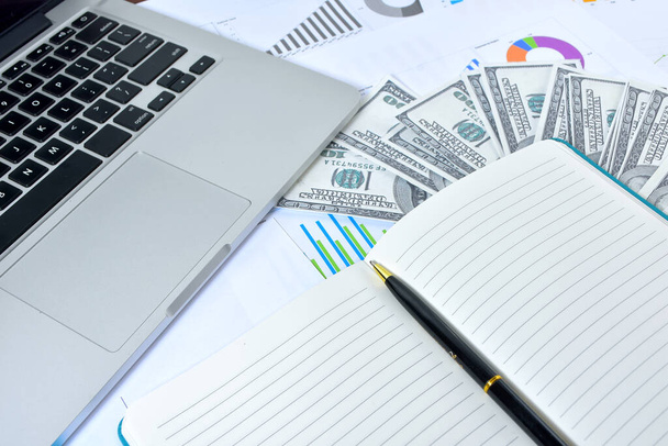 Geschäftskonzept. Laptop, Grafik und Banknote Dollar mit Notizbuch und Stift - Foto, Bild