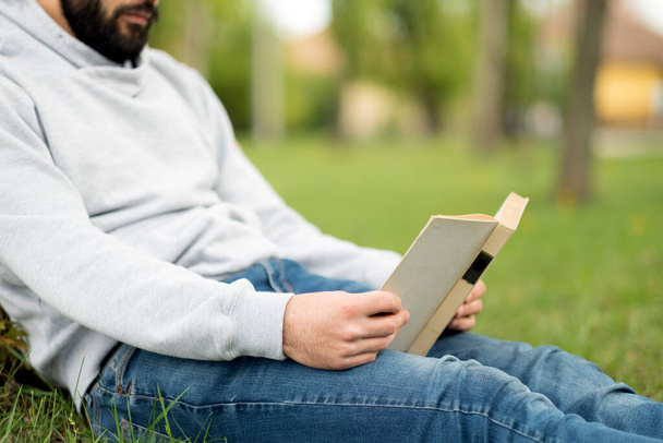 Mann liest Buch auf dem Rasen im Park - Foto, Bild