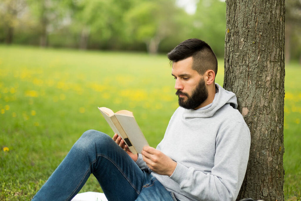 Junger Mann liest im Park ein Buch - Foto, Bild