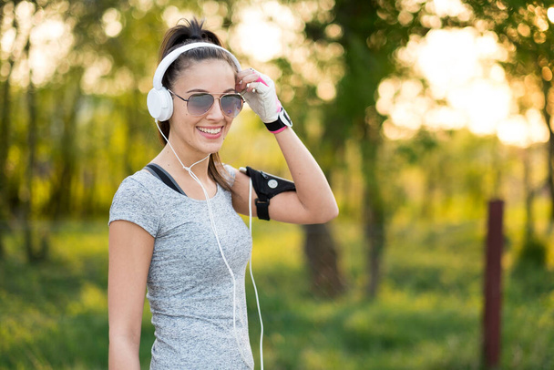 Νεαρή σέξι αθλητική γυναίκα που ακούει μουσική - Φωτογραφία, εικόνα