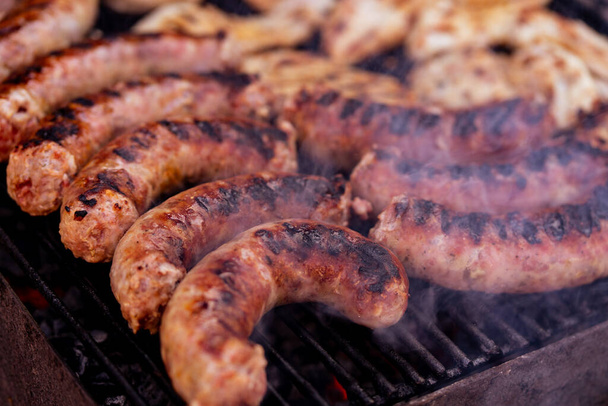 Pork meat and sausages grilled on a charcoal barbeque. Top view of tasty barbecue, food concept, food on grill and detail of food on the grill - Photo, Image