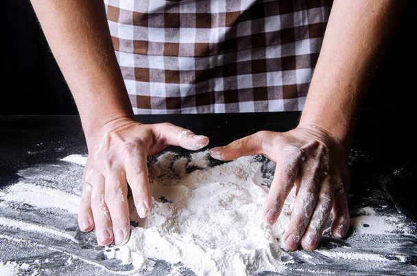 A man is preparing pizza dough. Men's hands in flour. Cooking homemade italian pizza. Preparation raw ingredients for baking - Foto, Imagen
