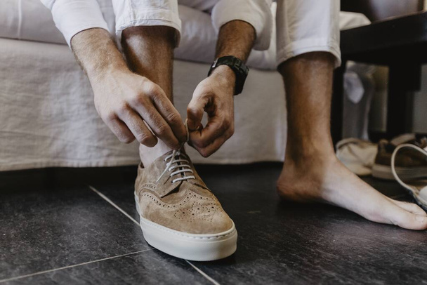 A horizontal shot of a man tying shoelaces of brown shoes - Zdjęcie, obraz