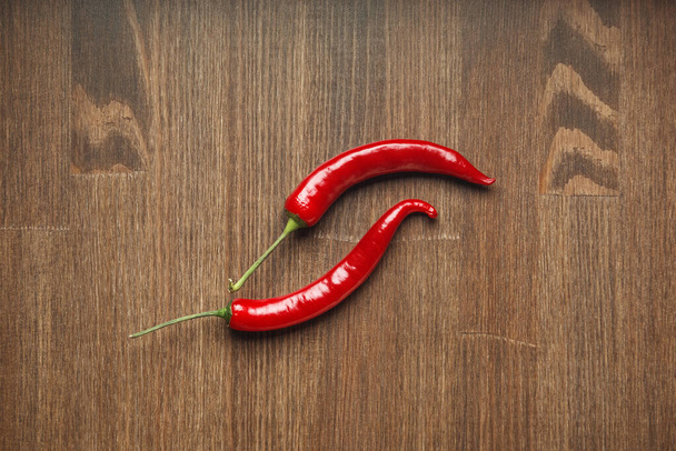 Two red ripe fruits of chili pepper on a wooden table - Photo, Image