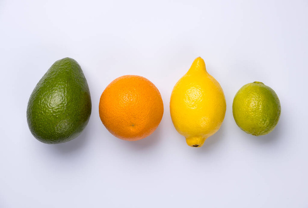 Close-up van citrusvruchten sinaasappel, citroen, avocado en kalk geïsoleerd op witte achtergrond. - Foto, afbeelding