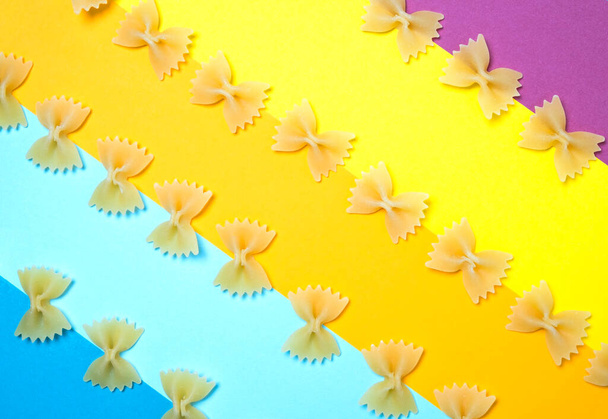 Primo piano modello di farfalle tagliatelle noto anche come papillon o pasta farfalla posto su sfondo colorato. - Foto, immagini