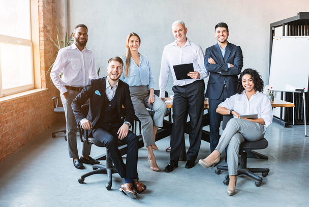 Επιτυχημένη επιχειρηματική ομάδα Ποζάροντας χαμογελώντας στην κάμερα στο σύγχρονο γραφείο - Φωτογραφία, εικόνα