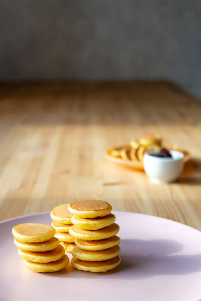 Stacks trendy tiny pancakes on pink plate. - 写真・画像