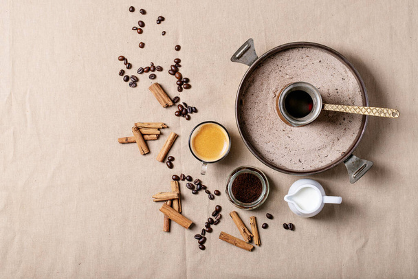Fresh coffee in glass cups with cinnamon sticks over brown cloth background. Top view, flat lay - Photo, image