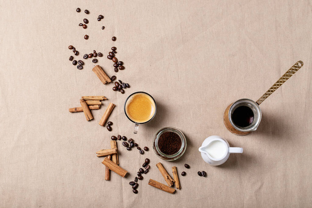 Fresh coffee in glass cups with cinnamon sticks over brown cloth background. Top view, flat lay - Foto, afbeelding
