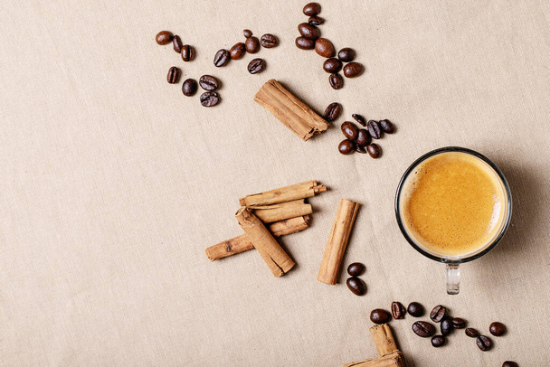 Fresh coffee in glass cups with cinnamon sticks over brown cloth background. Top view, flat lay - Foto, Bild