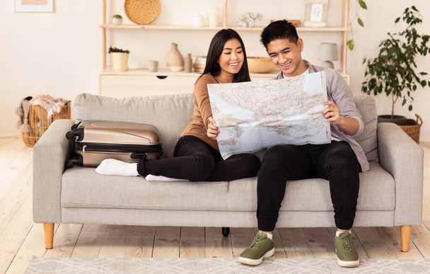 Asian para gospodarstwa Mapa świata siedzi na kanapie w domu - Zdjęcie, obraz