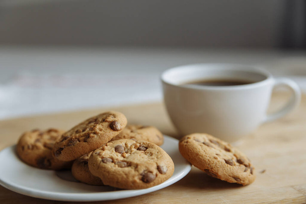 brown cookies on the white plate and coffee in white glass - Фото, зображення