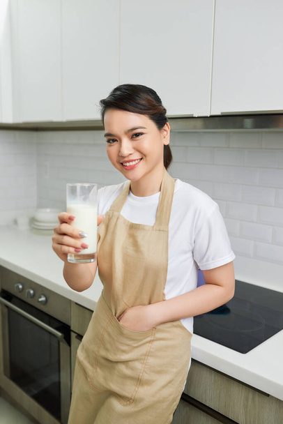 Jovem mulher atraente com leite e café da manhã saudável na cozinha - Foto, Imagem