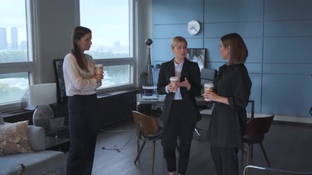 three business women drink coffee and chat about new projects during a break in their office - Кадри, відео