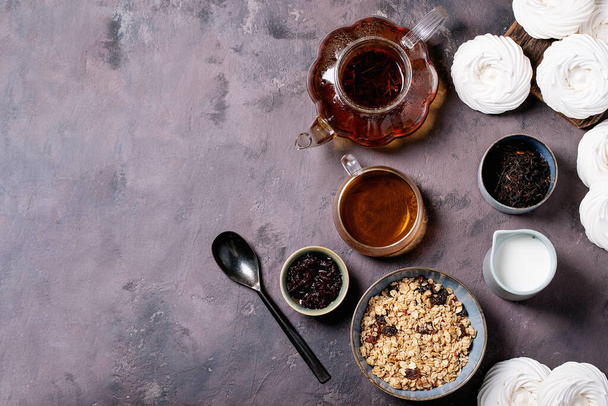 Granola breakfast in ceramic bowl served with fresh milk, cranberry jam and black tea over brown texture background. Top View - Photo, Image