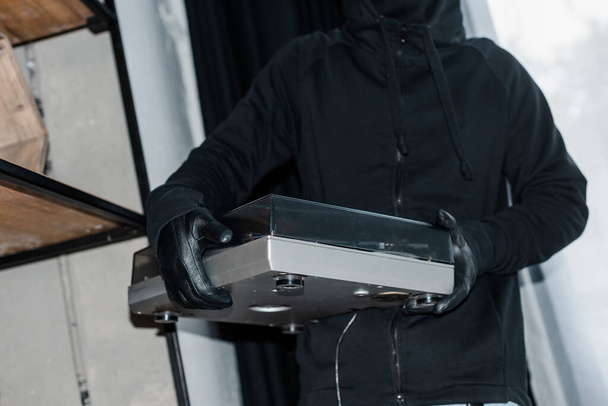 Обрезанный вид грабителя в кожаных перчатках с магнитофоном во время кражи
 - Фото, изображение
