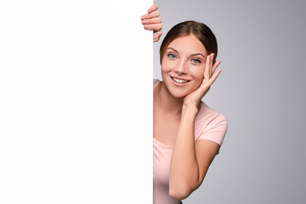 Smiling woman peeking out from behind white banner - Photo, Image