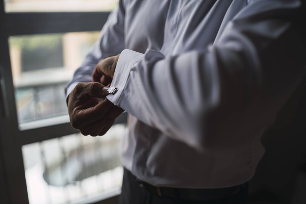 A high angle closeup shot of a man in a white shirt adjusting his sleeves - Foto, Imagem
