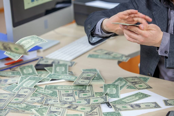 A young businessman working from his office and counting cash money - Foto, imagen