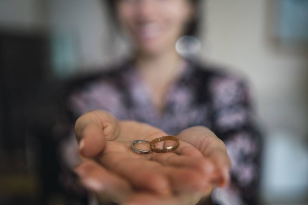 A selective focus shot of a female holding wedding rings in her hands - Fotó, kép