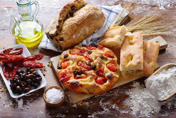 Focaccia Barese e prodotti da forno su un piano di lavoro infarinato. Ingredienti e condimenti tipici della dieta mediterranea
. - Foto, immagini