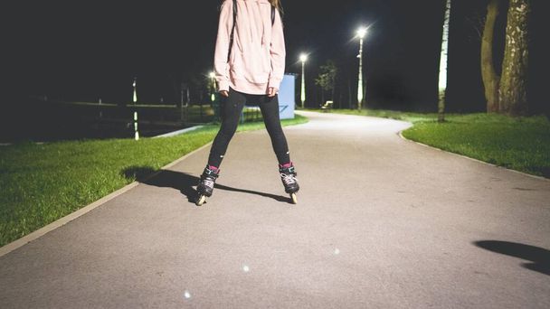 A young female rollerblading in the park at night - Foto, immagini