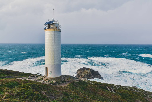 A beautiful lighthouse in the cliffs with the magnificent stormy sea in the background - Foto, Imagem
