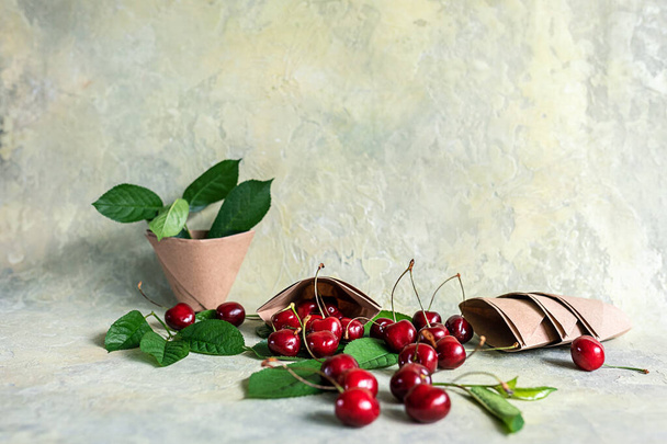 Paper cups or origami bags, containers with cherries. Eco-friendly food packaging, on an abstract beautiful background with a copy space. The preservation of nature and the concept of recycling. selective focus. - Foto, Bild