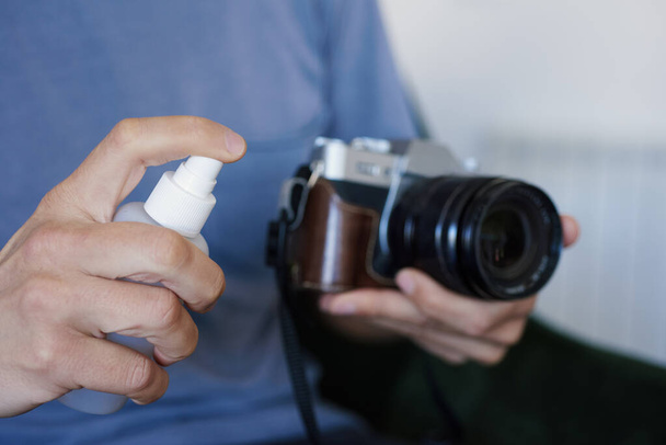 primo piano di un uomo caucasico che disinfetta la macchina fotografica spruzzando un disinfettante da una bottiglia
 - Foto, immagini