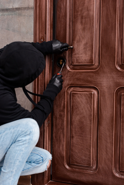 Kapı kilidini tornavidayla açan ev hırsızının yan görünümü  - Fotoğraf, Görsel