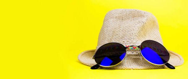 Nők nyári szalma kalap egy karimás, kék lekerekített napszemüveg sárga háttér oldalnézeti fénymásolás helyet. Zászlós. - Fotó, kép