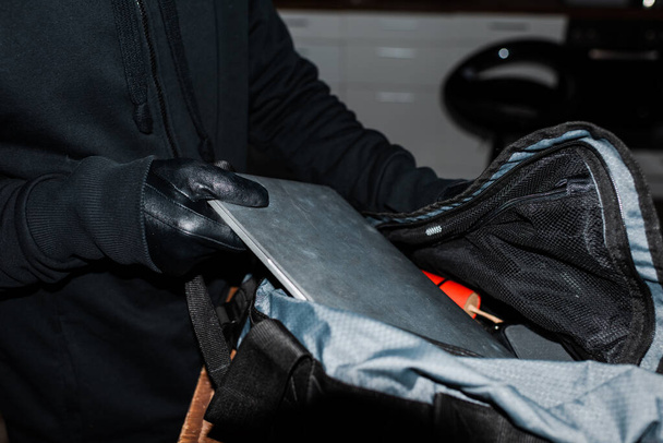 Vista recortada de ladrón poner portátil en bolsa con dinamita
  - Foto, imagen